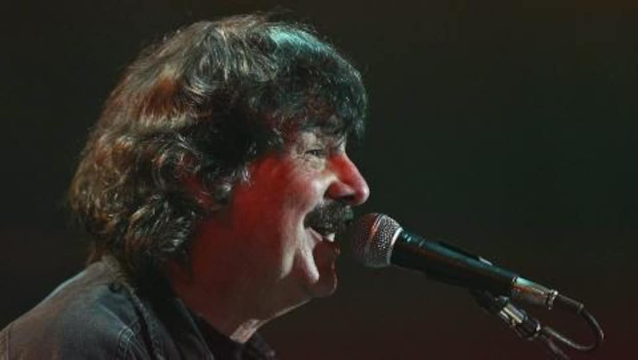 Burton Cummings, devant un micro, chante pendant un concert.