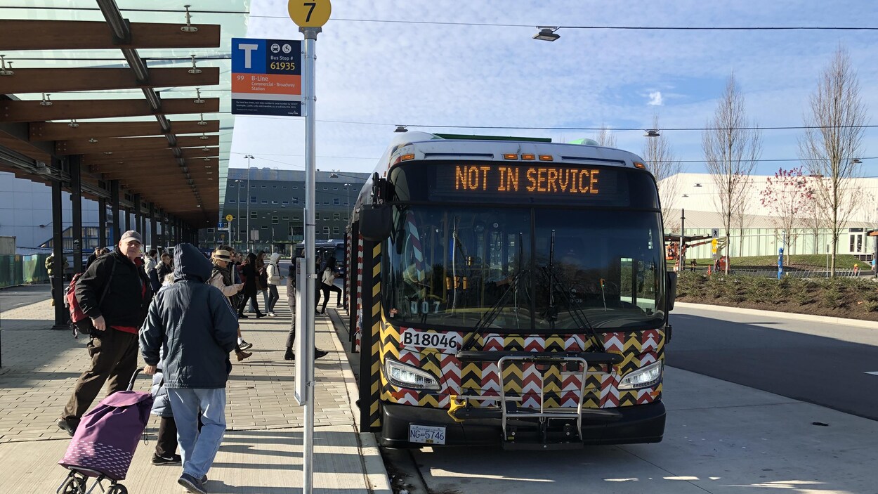 Un autobus à l'arrêt et des gens qui s'apprêtent à y monter.