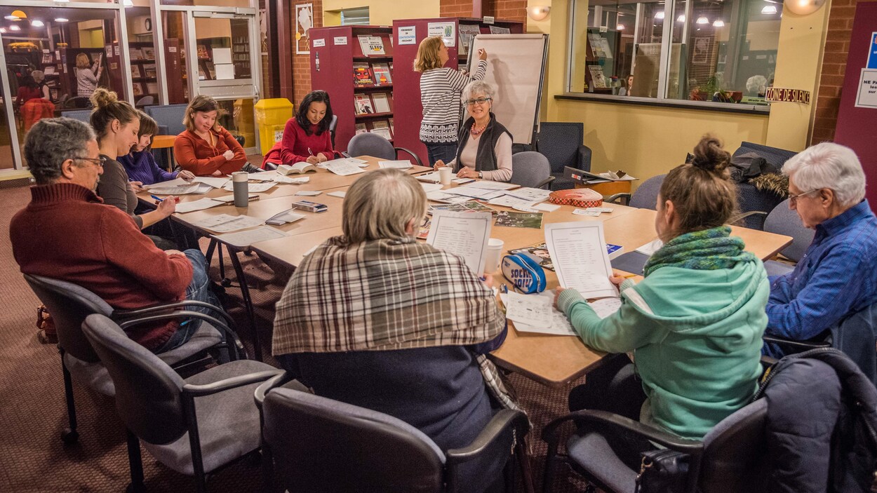 Les participants et les animateurs bénévoles sont assis autour d'une table. Les participants et les animateurs bénévoles sont assis autour d'une table.
