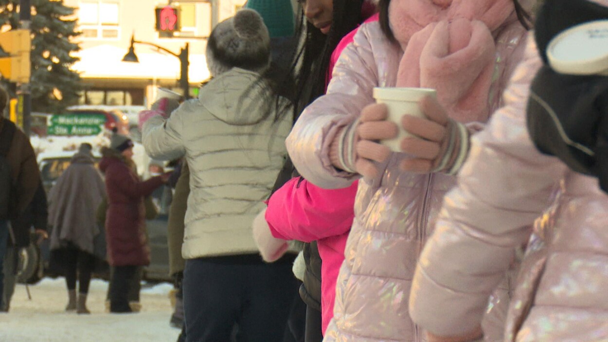 Des élèves se passent des bols de soupe dans une rue du centre-ville de Sudbury.
