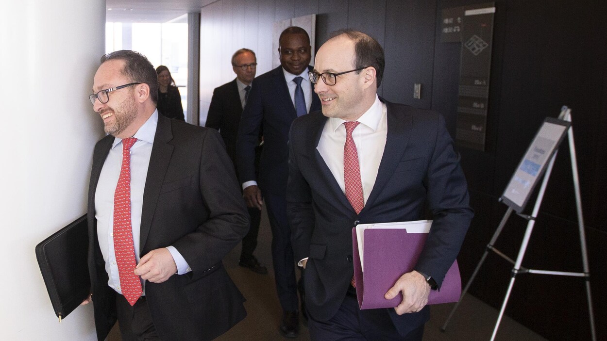 Deux hommes d'affaires marchent dans un couloir.