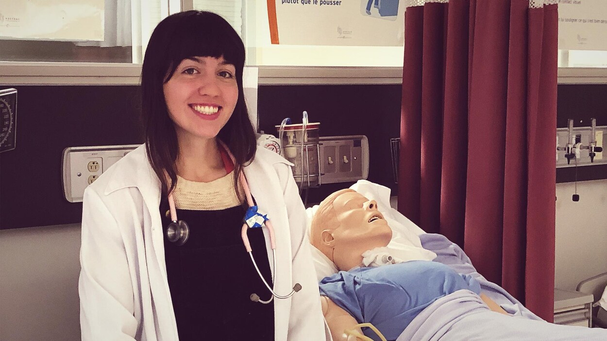 L'étudiante se trouve devant un lit d'hôpital, où un faux patient est allongé