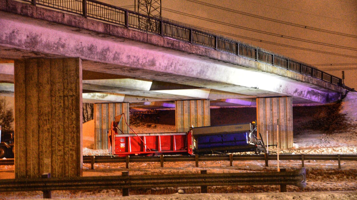 Un camion benne immobilité sous le viaduc d'une autoroute.