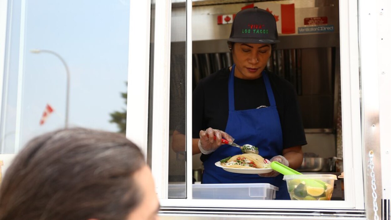 Une femme prépare des tacos dans un camion.