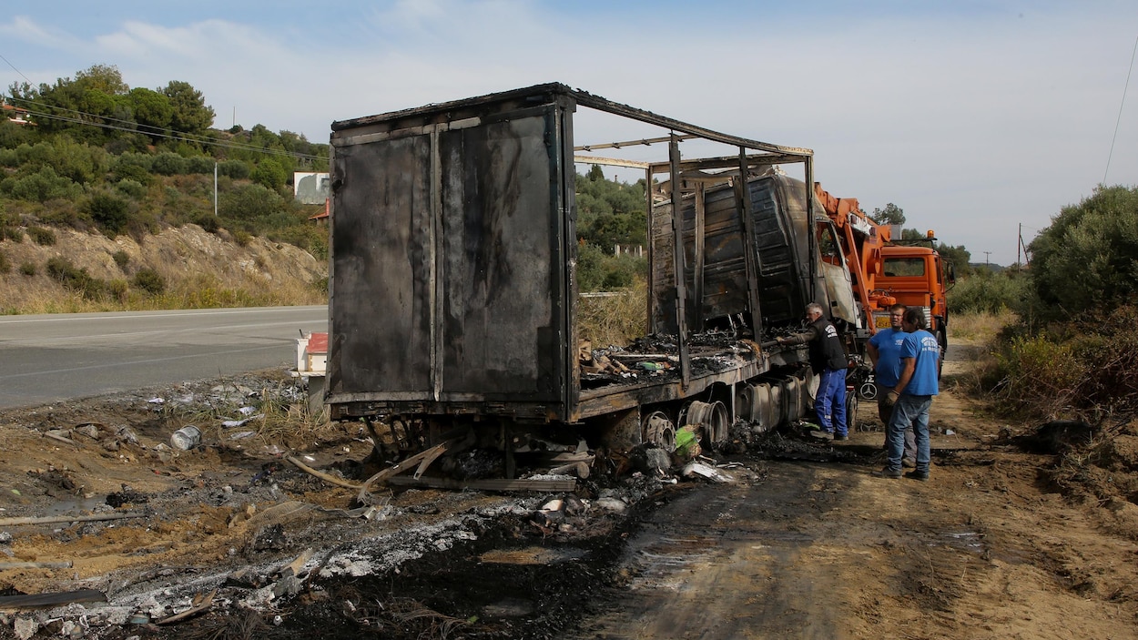 Trois personnes près d'un camion calciné, sur le bord d'une route en campagne. Trois personnes près d'un camion calciné, sur le bord d'une route en campagne.