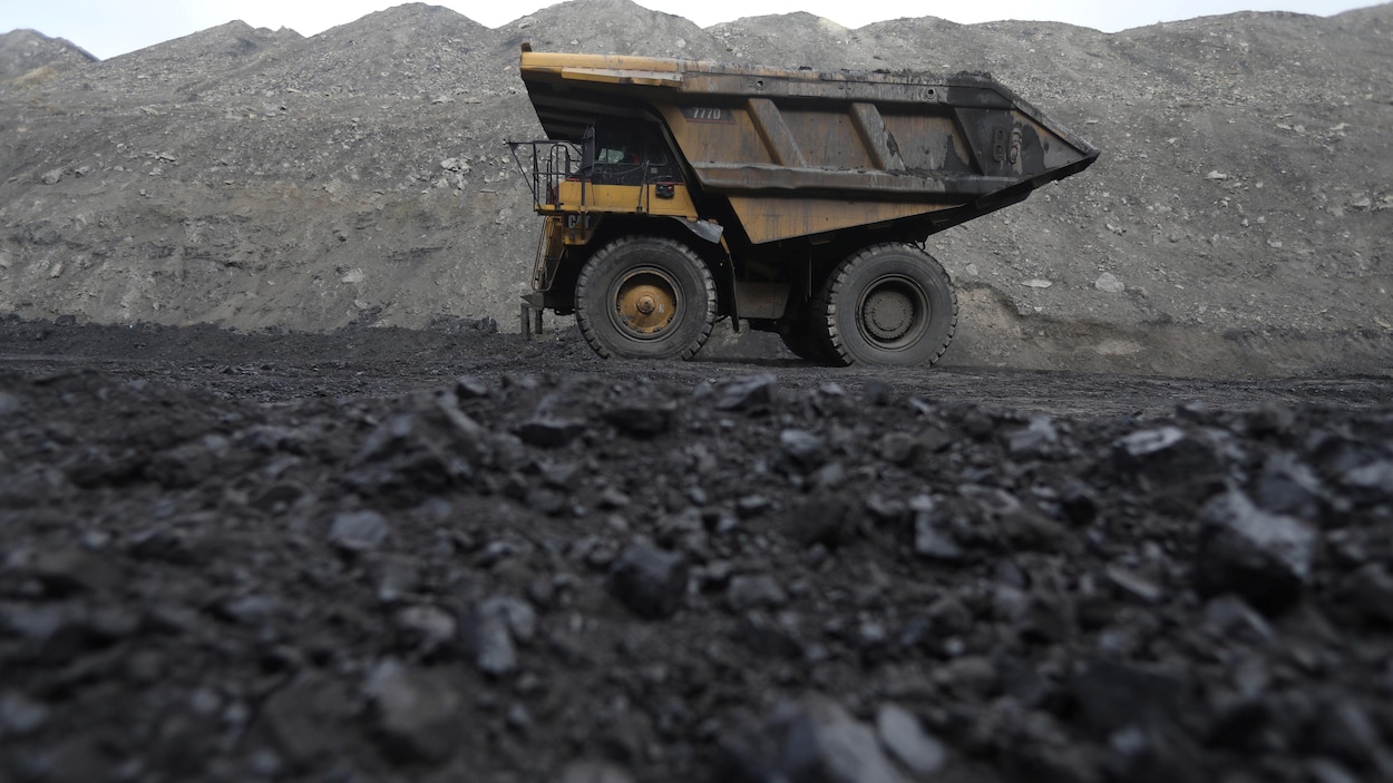 Un camion roule sur une terre noircie par le charbon