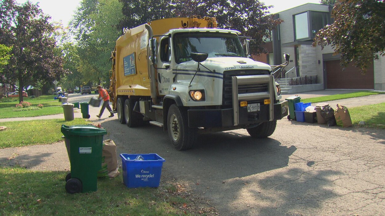 Un camion-poubelle de la Ville d'Ottawa circule dans une rue résidentielle.