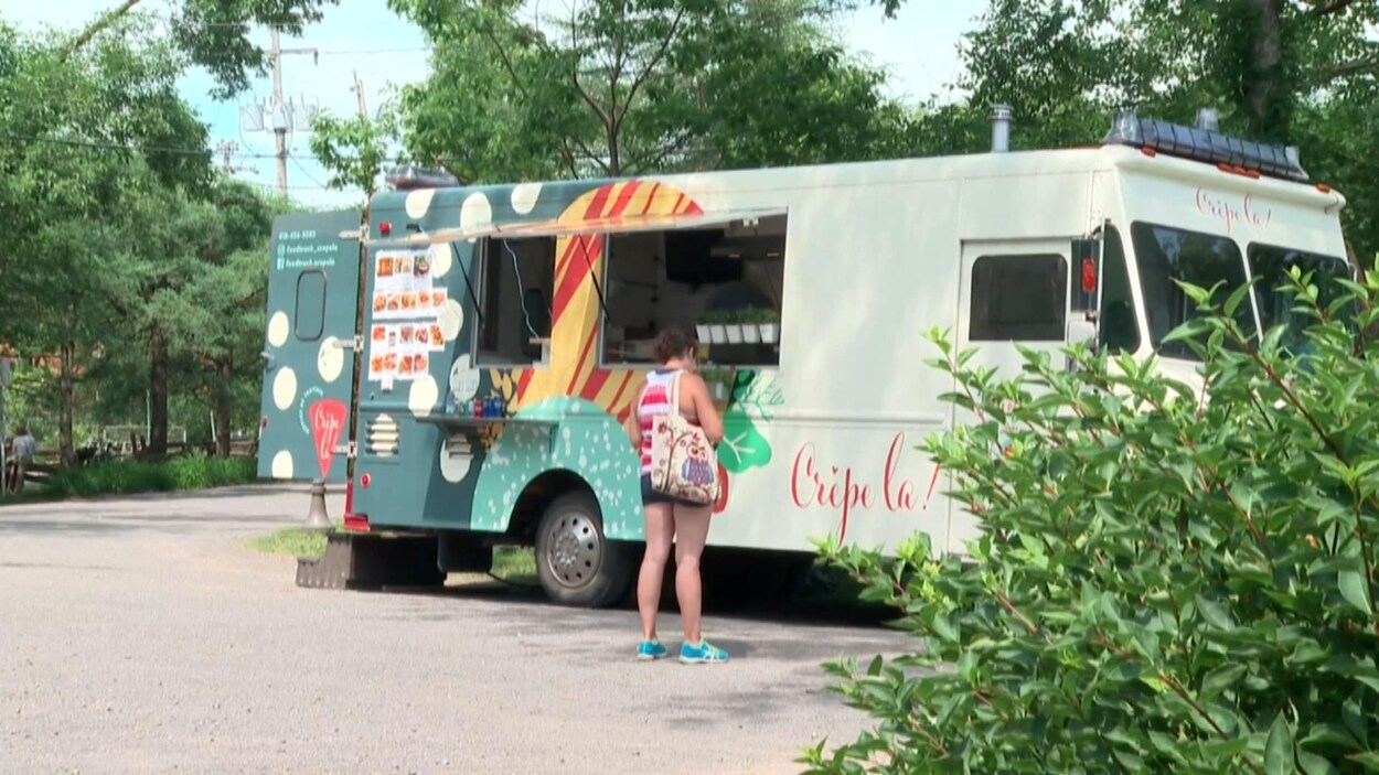 Le camion de cuisine de rue Crêpe là! dans un parc. Une cliente attend son repas.