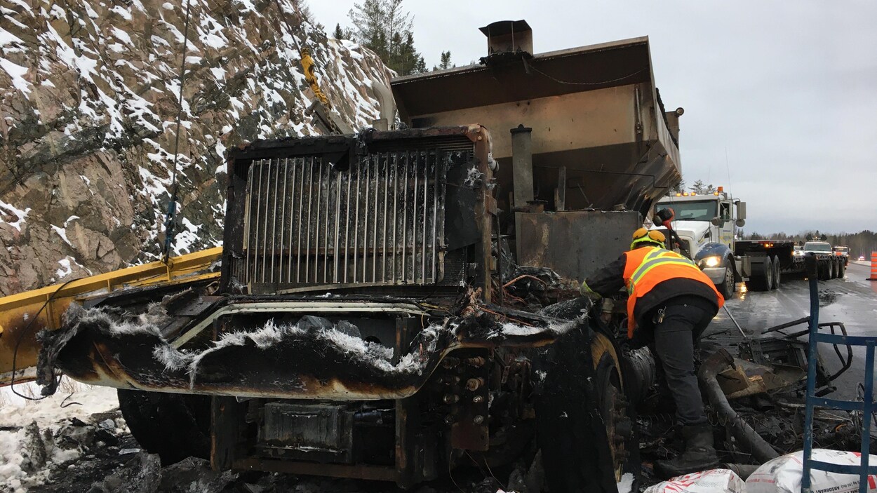 Un travailleur s'affaire autour de la carcasse du camion.