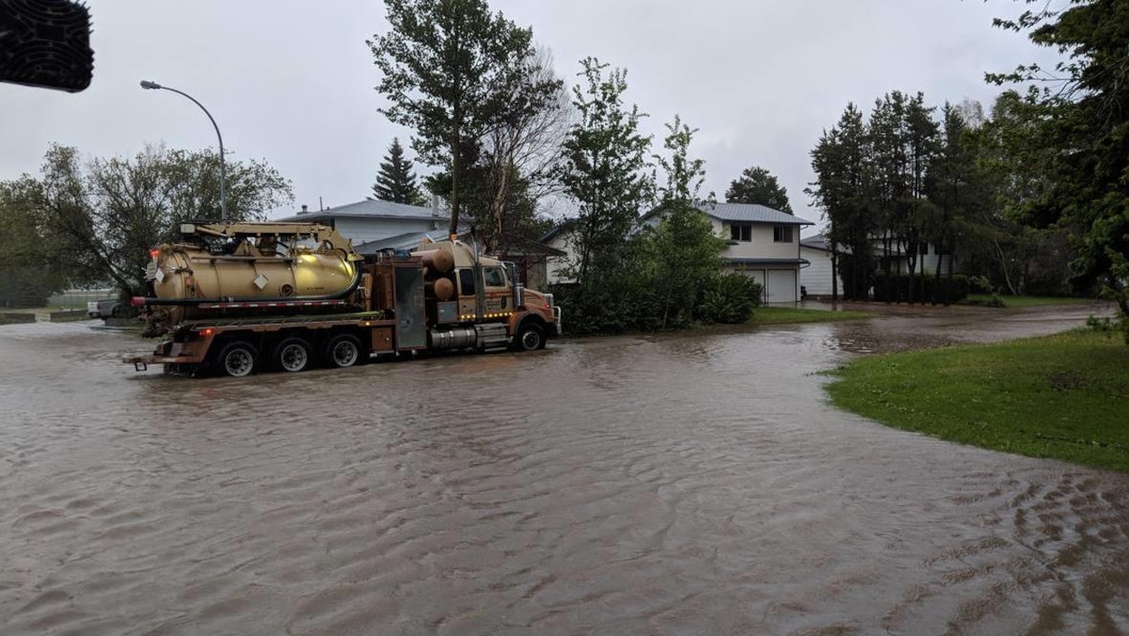 Un camion-pompe circule dans une rue inondée d'un quartier résidentiel. Un camion-pompe circule dans une rue inondée d'un quartier résidentiel.