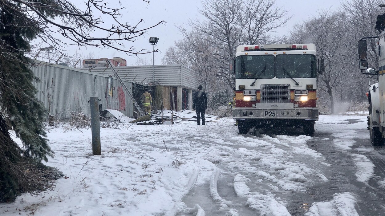 Un camion de pompier garé devant une immeuble sinistré en hiver.