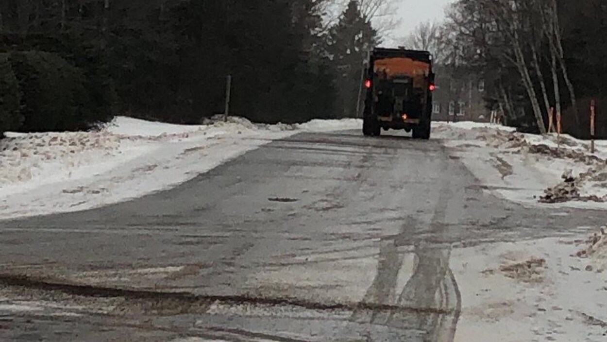 Le camion progresse lentement sur une route rurale recouverte de verglas