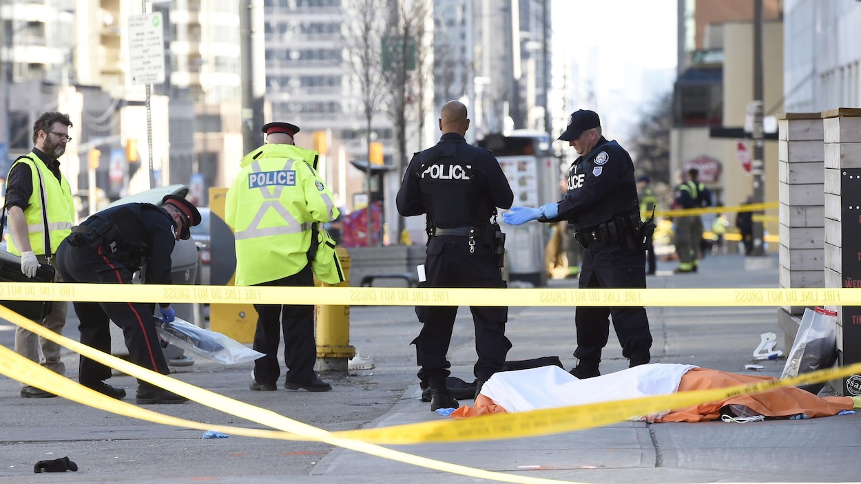 Des policiers torontois recueillent des objets près du corps d'une des victimes.