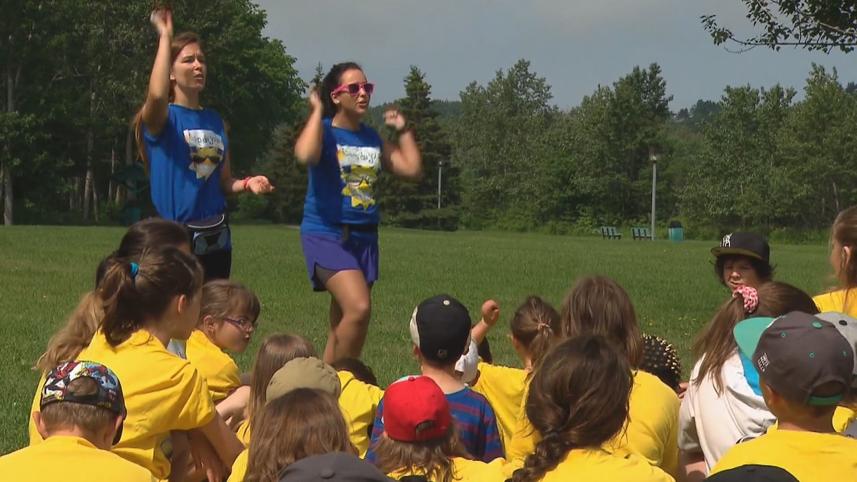 Des monitrices devant un groupe de jeunes dans un camp de jour.