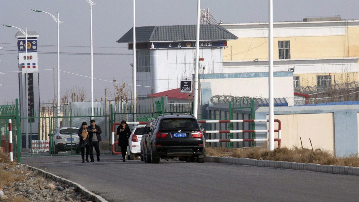Des gens marchent dans une rue qui mène à un centre de détention.