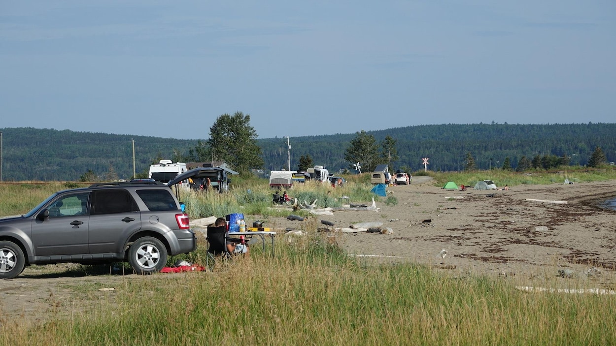 Des tentes et des véhicules sont installés sur une plage.
