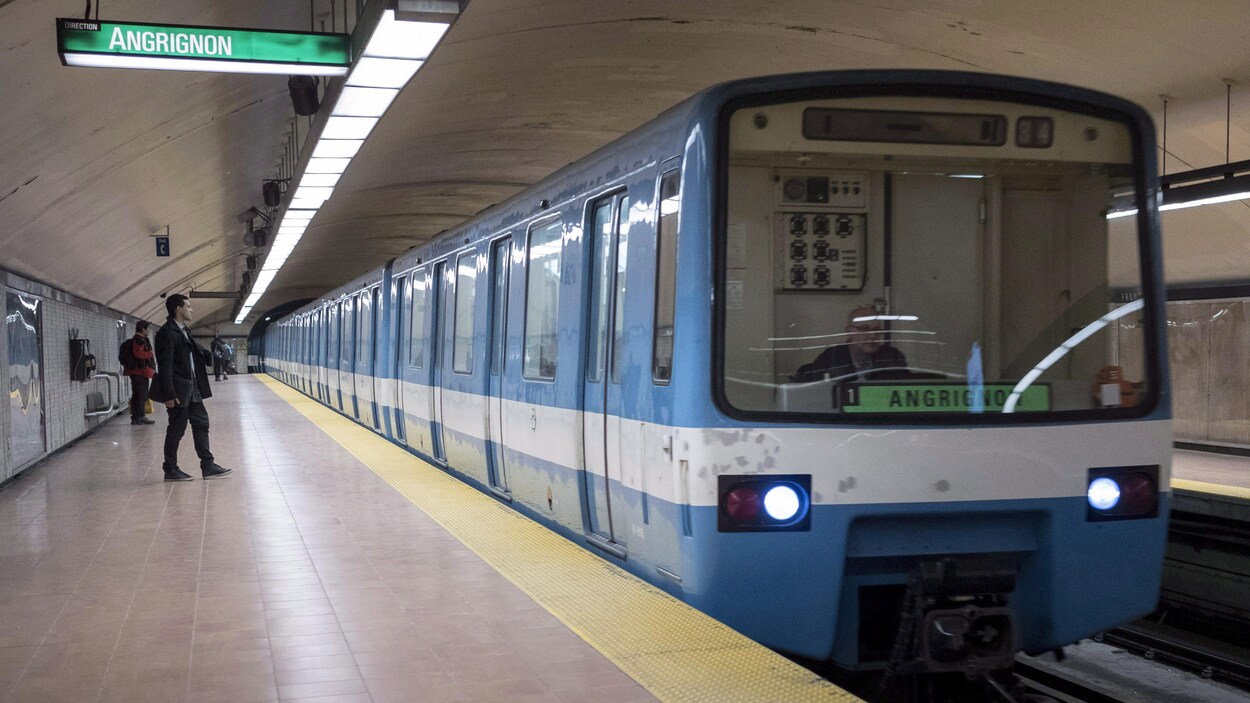 Une rame de métro bleue arrive dans une station.