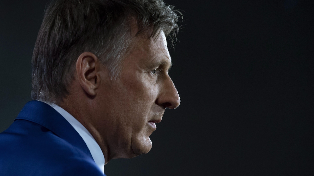 Maxime Bernier, de profil, l'air sérieux, photographié du niveau des épaules jusqu'au haut de la tête.