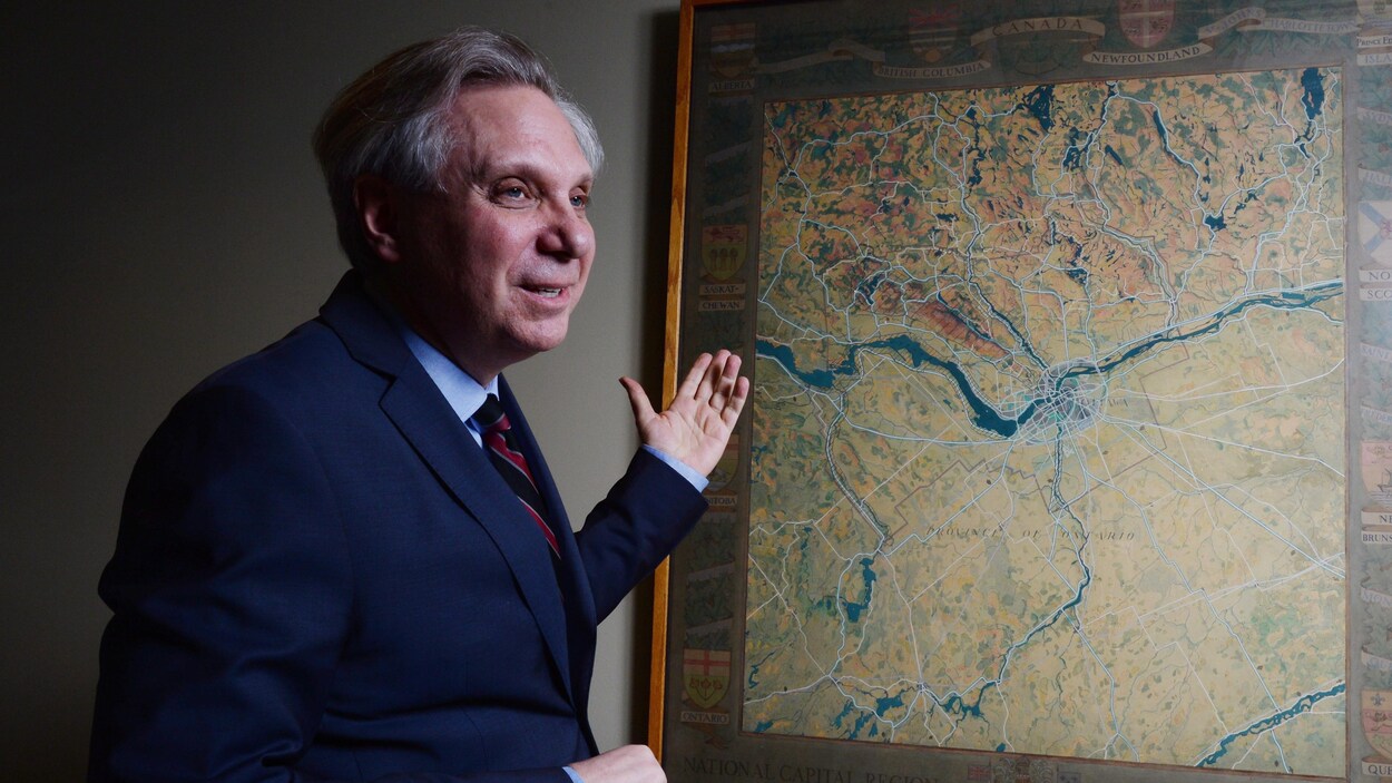 Mark Kristmanson regarde une carte de la région de la capitale nationale dans un bureau.