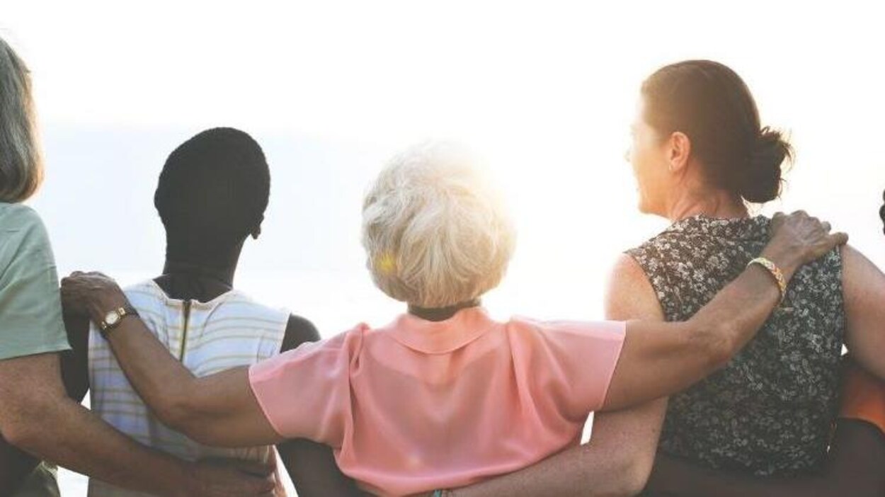 Des femmes, de dos, se tiennent par la taille et regardent le soleil devant elles,