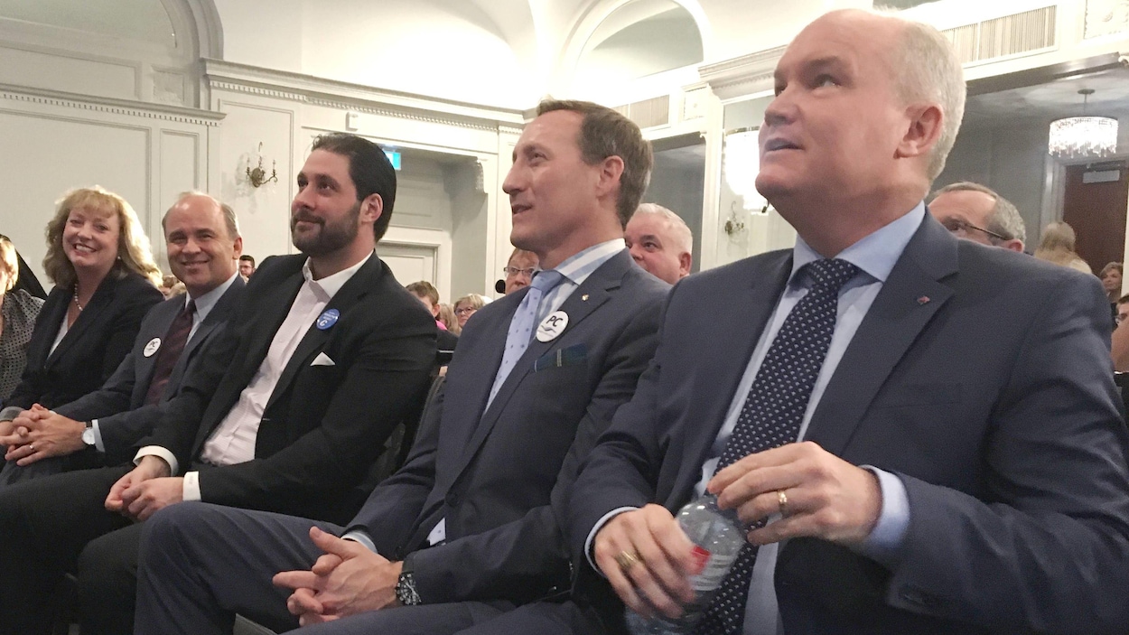 Cinq candidats à la direction du Parti conservateur du Canada sont assis en rang sur des chaises.