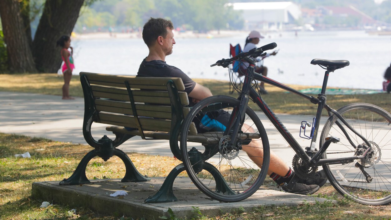 Une personne assise sur un banc avec sa bicyclette.