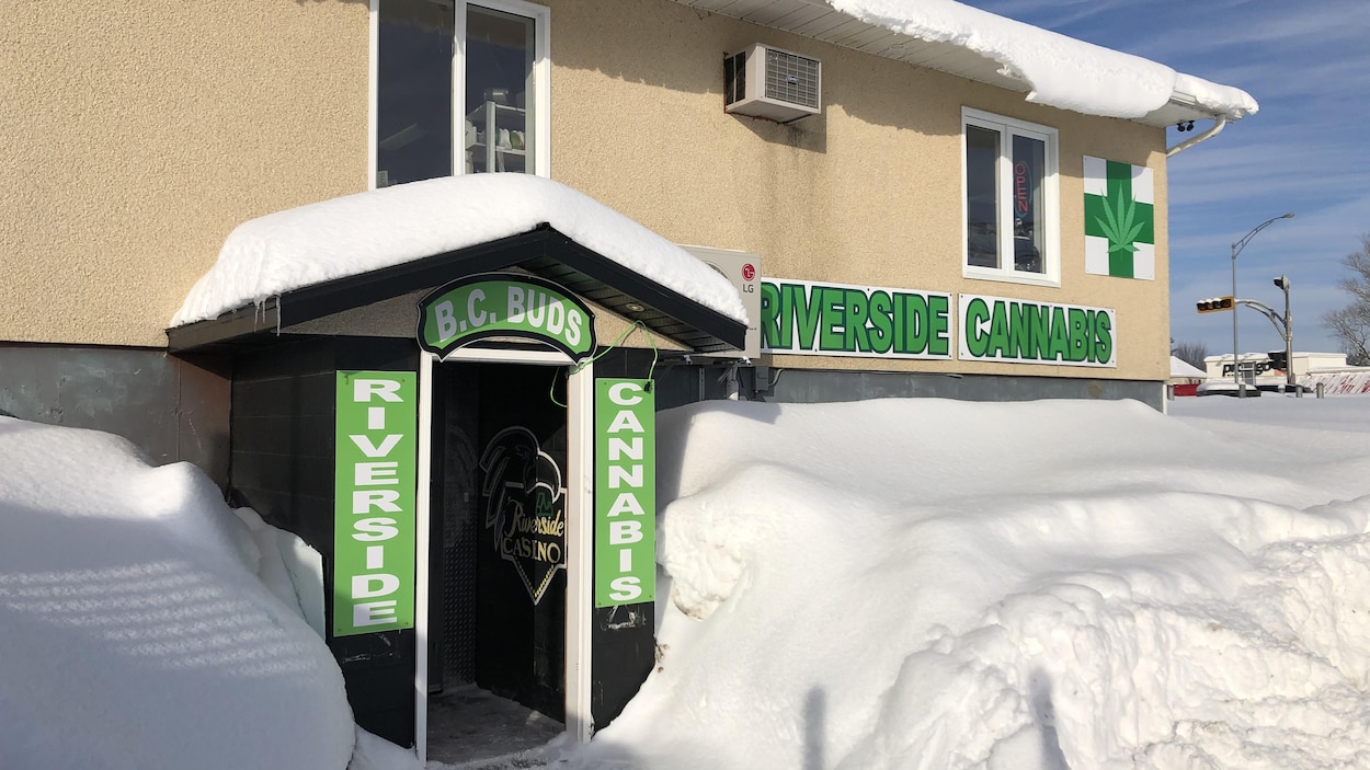 L'entrée d'un commerce avec des affiches indiquant « Riverside cannabis ».
