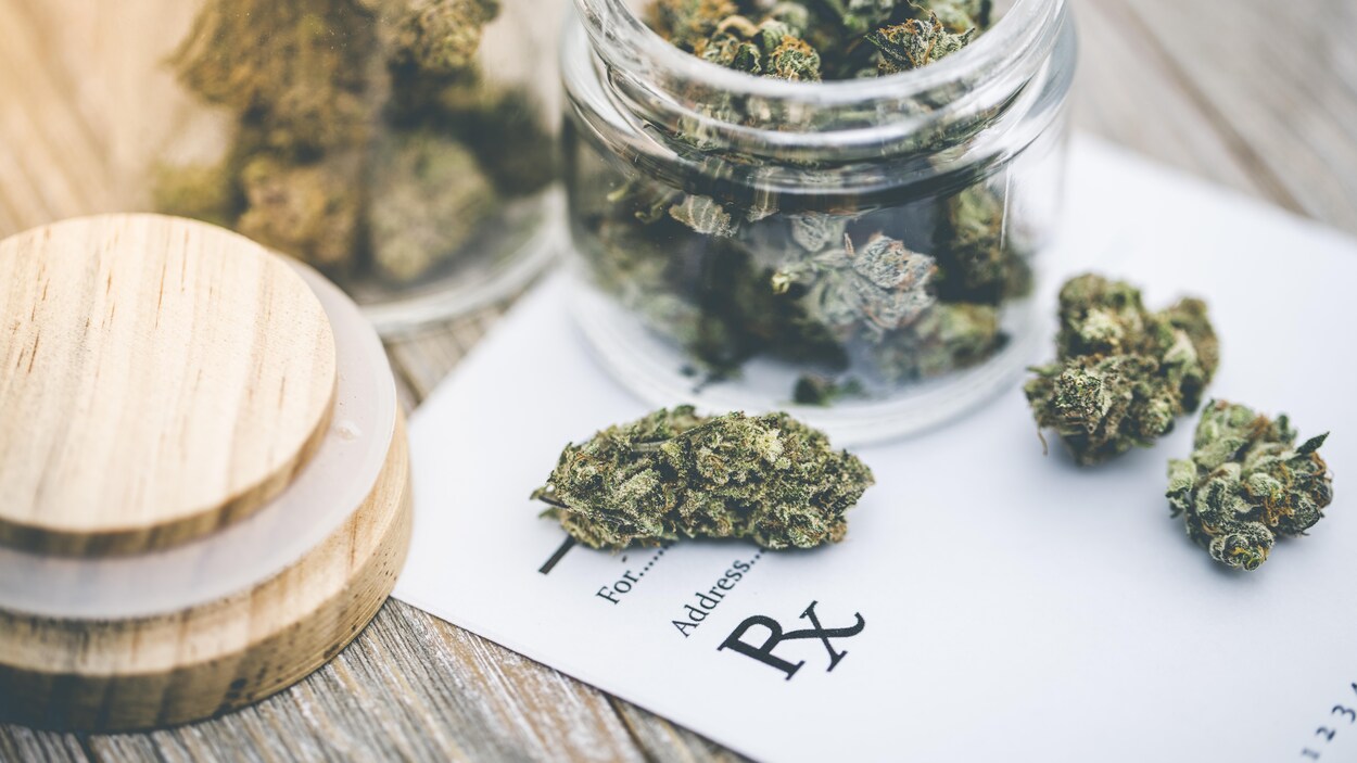 Un bocal en verre rempli de cannabis séché.