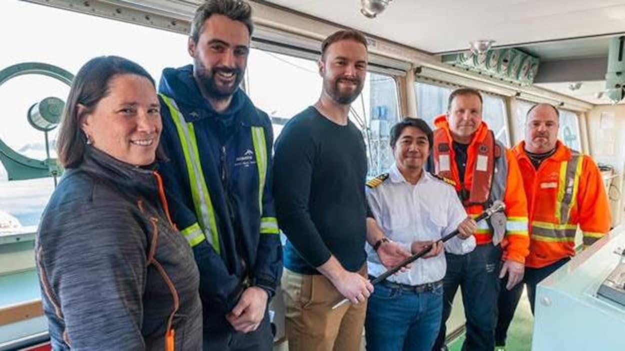 Le capitaine Santos tient la canne à pommeau d'acier, entouré de cinq autres personnes.