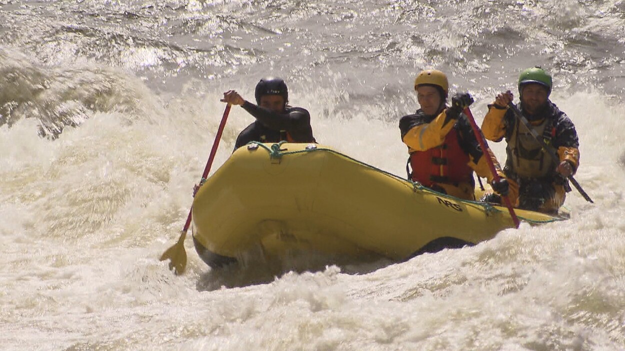 Trois personnes descendent une rivière en rafting.