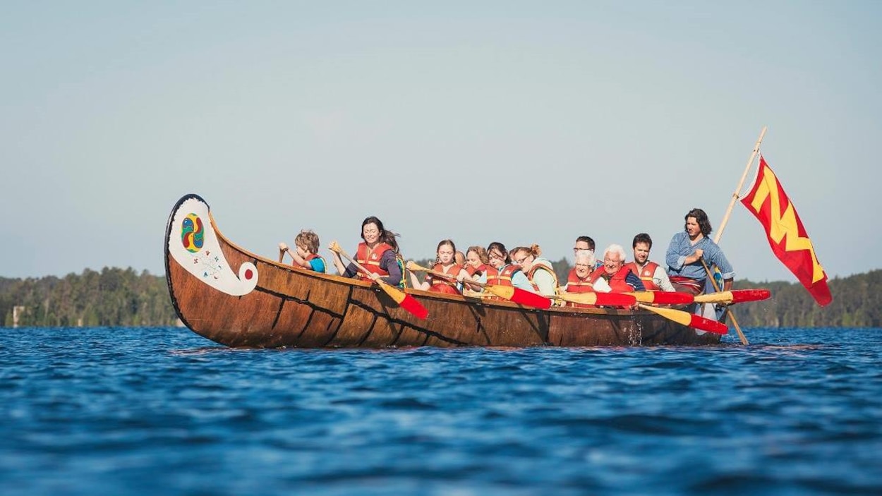 Des personnes dans un grand canot d'écorce.