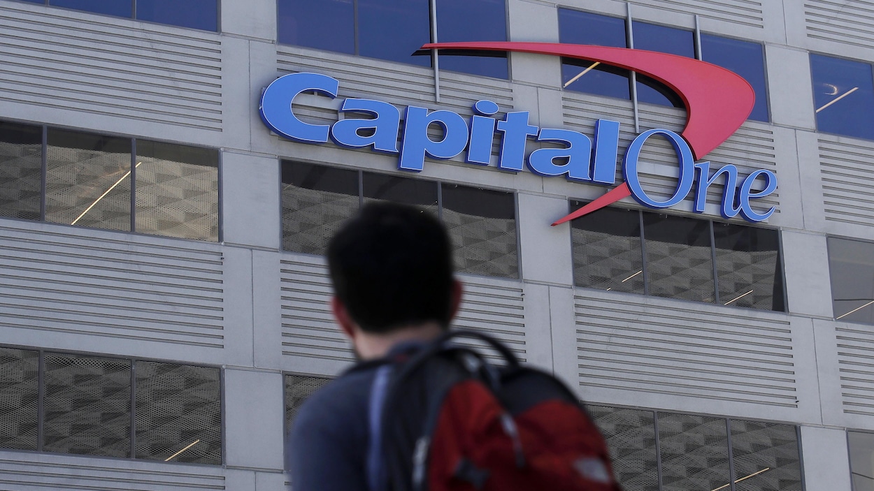 Un homme regarde au loin l'enseigne de Capital One sur un édifice.