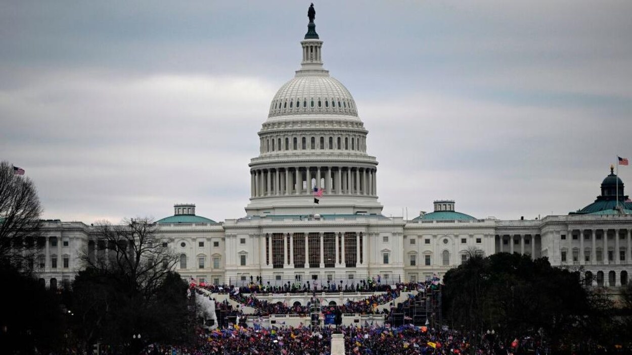 Vue d'ensemble de l'extérieur du Capitole, devant lequel des milliers de personnes sont réunies.