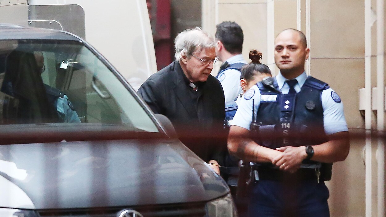 Menotté, un vieil homme sortant d'un véhicule est escorté par des policiers.