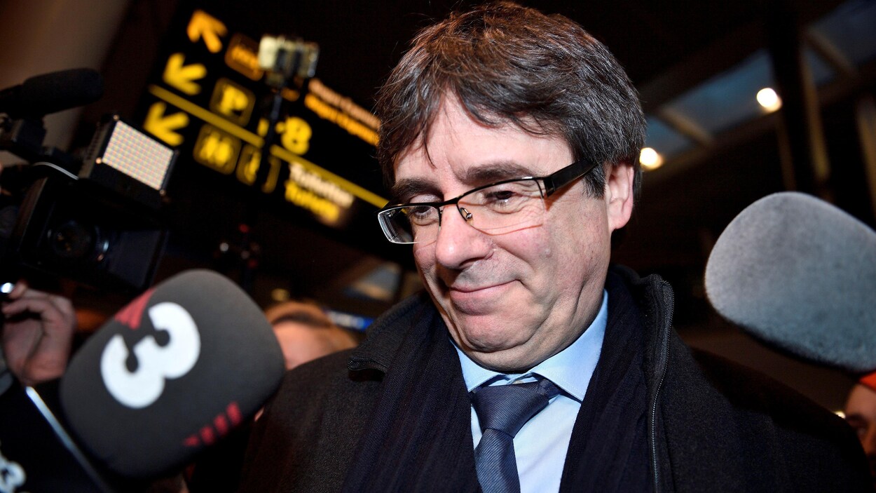 Carles Puigdemont sourit devant deux micros. Carles Puigdemont sourit devant deux micros.