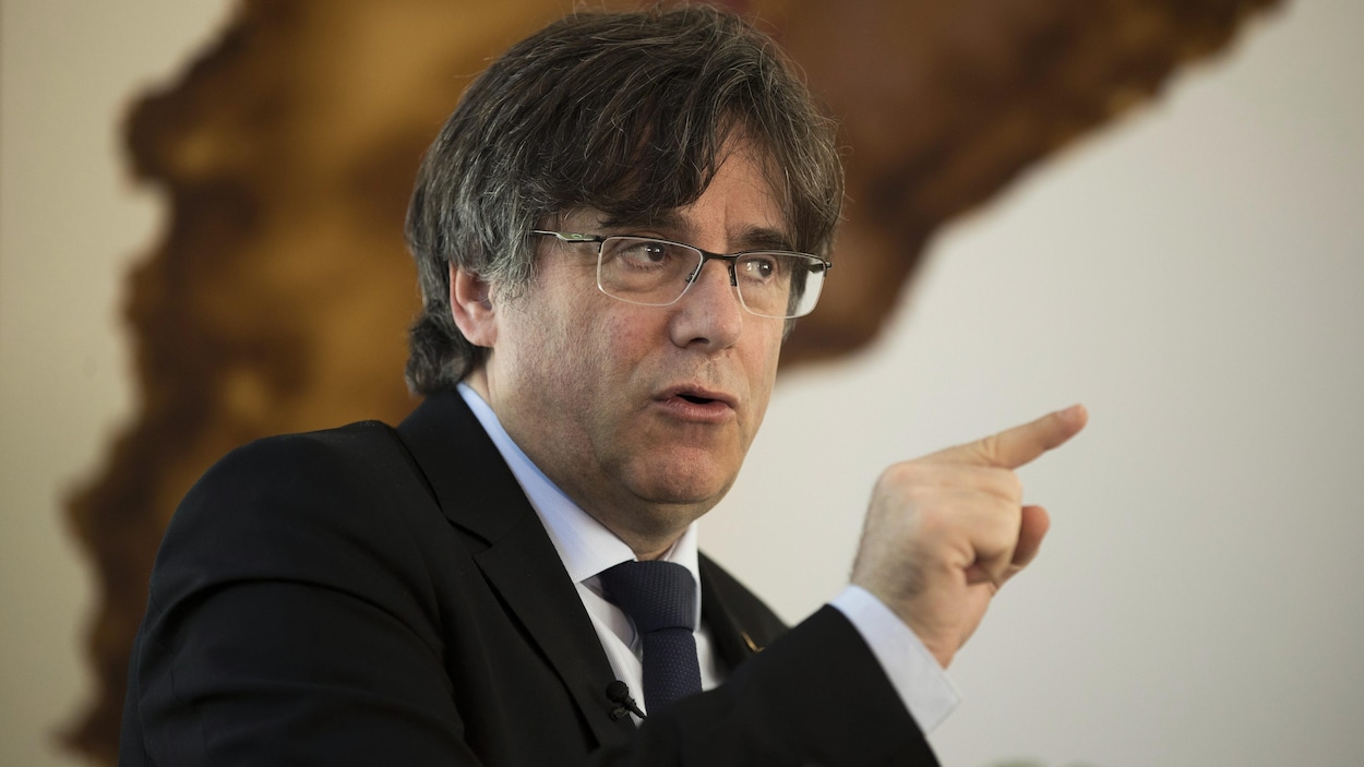 L’ex-président de la Catalogne, Carles Puigdemont, affiche un air sévère et a levé l'index qu'il pointe d'une façon accusatrice.