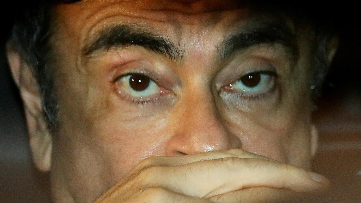 Gros plan de Carlos Ghosn, les mains devant le visage.