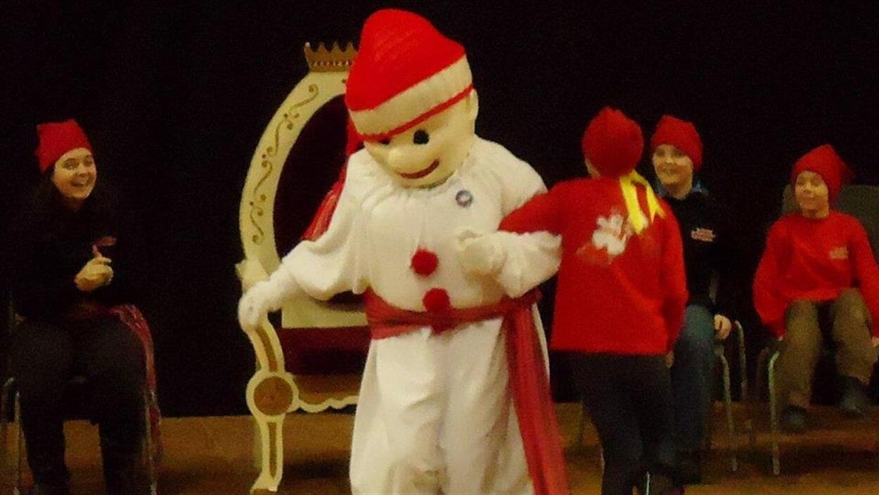 Une mascotte du Bonhomme Carnaval s'asseoit sur un trône.