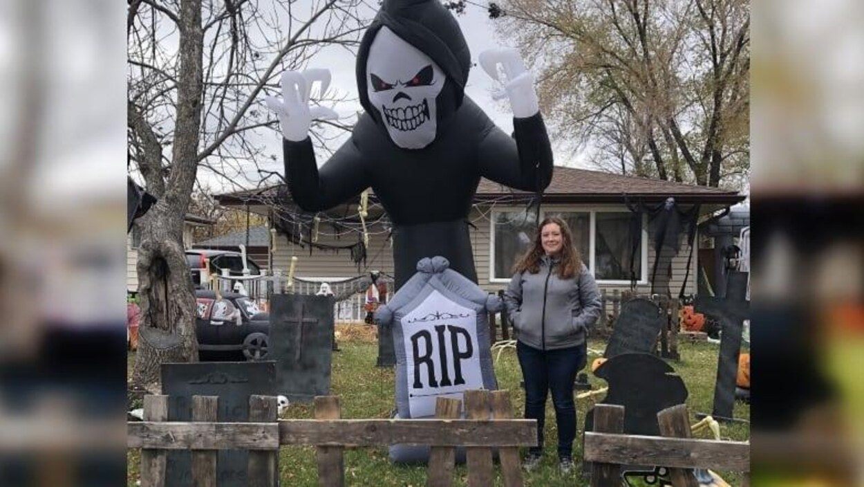 Carol Cassell se tient fièrement parmi des décorations d'Halloween installées sur le terrain avant de sa maison