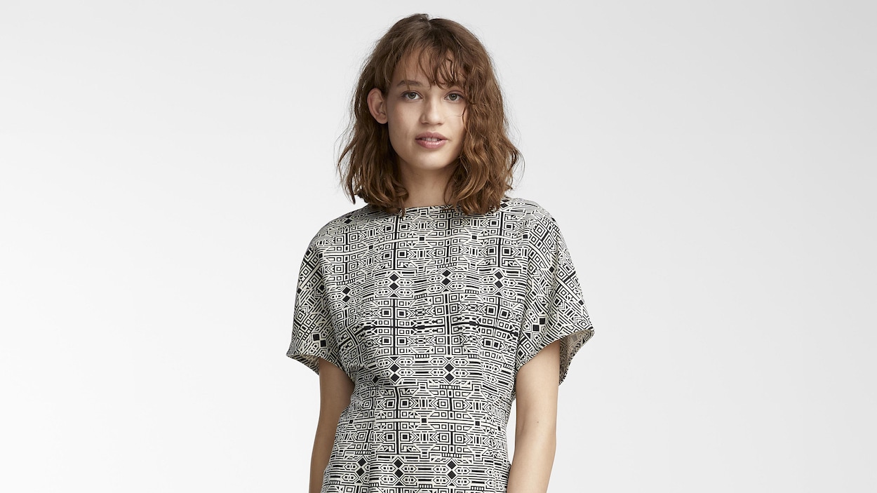 Une femme porte une robe arborant un motif noir et blanc.