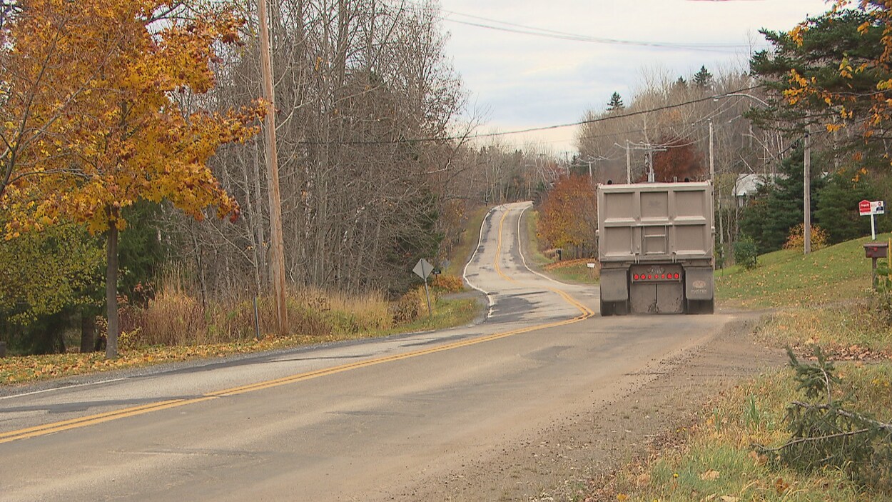 Un camion lourd circule dans un chemin résidentiel.