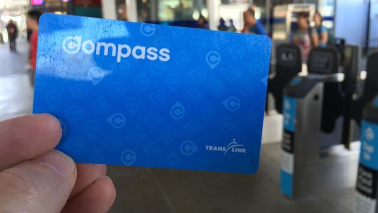 Une carte Compass de Translink devant des bornes d'une station de skytrain