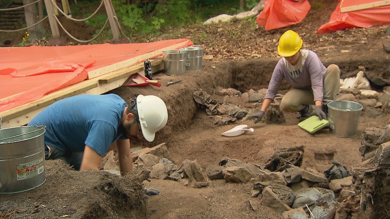 Deux archéologues procèdent au nettoyage d'un carré de fouilles du site Cartier-Roberval à Québec.