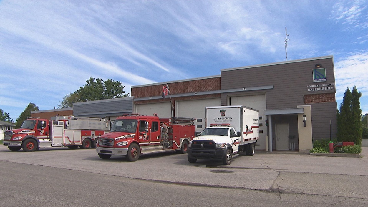 Deux camions de pompier et un troisième portant l'inscription « Unité de soutien » sont stationnés devant une caserne sur laquelle on voit clairement le logo de la Ville de Trois-Rivières.
