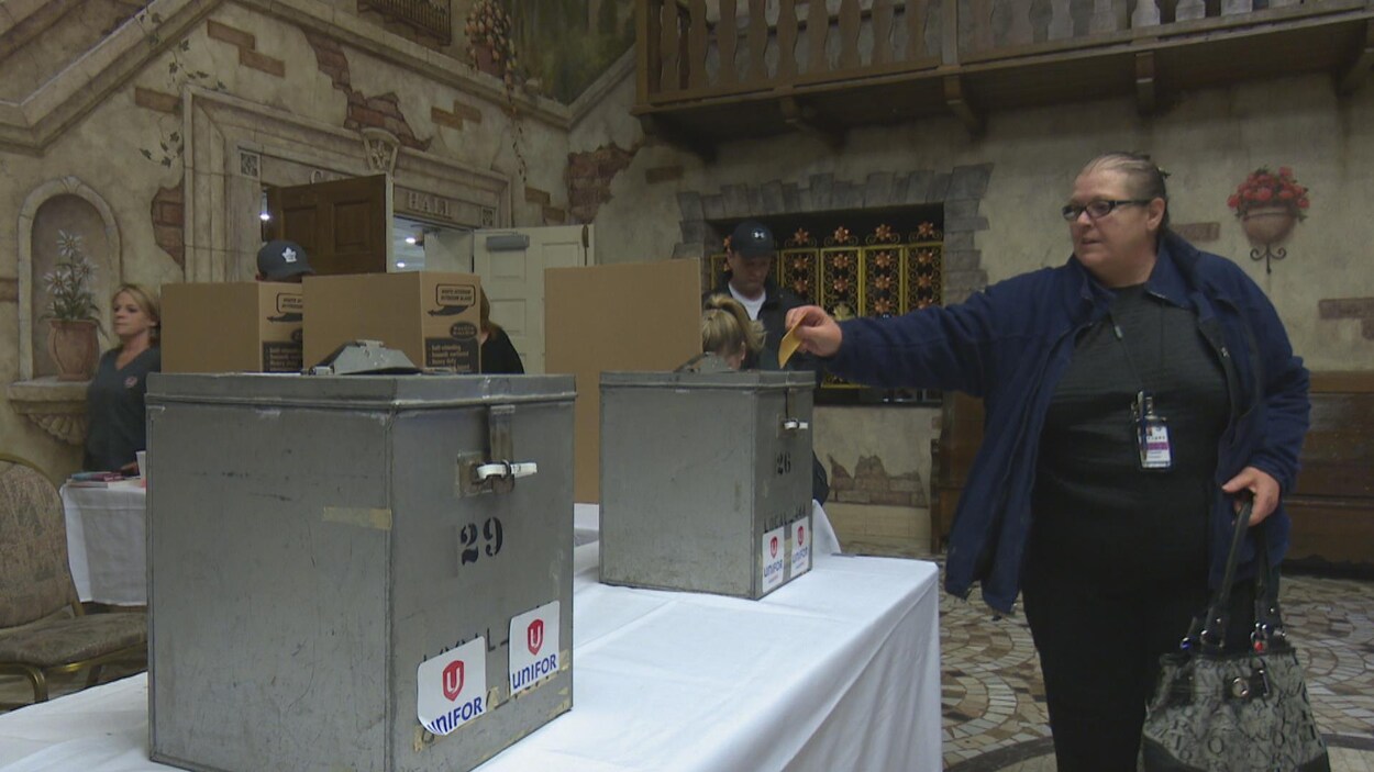 Une femme place un bulletin de vote dans une grosse boîte en métal gris. Une femme place un bulletin de vote dans une grosse boîte en métal gris.