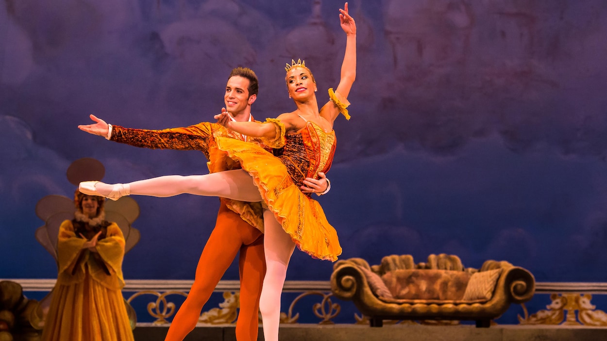 Un danseur et une danseuse faisant une arabesque sont sur scène.