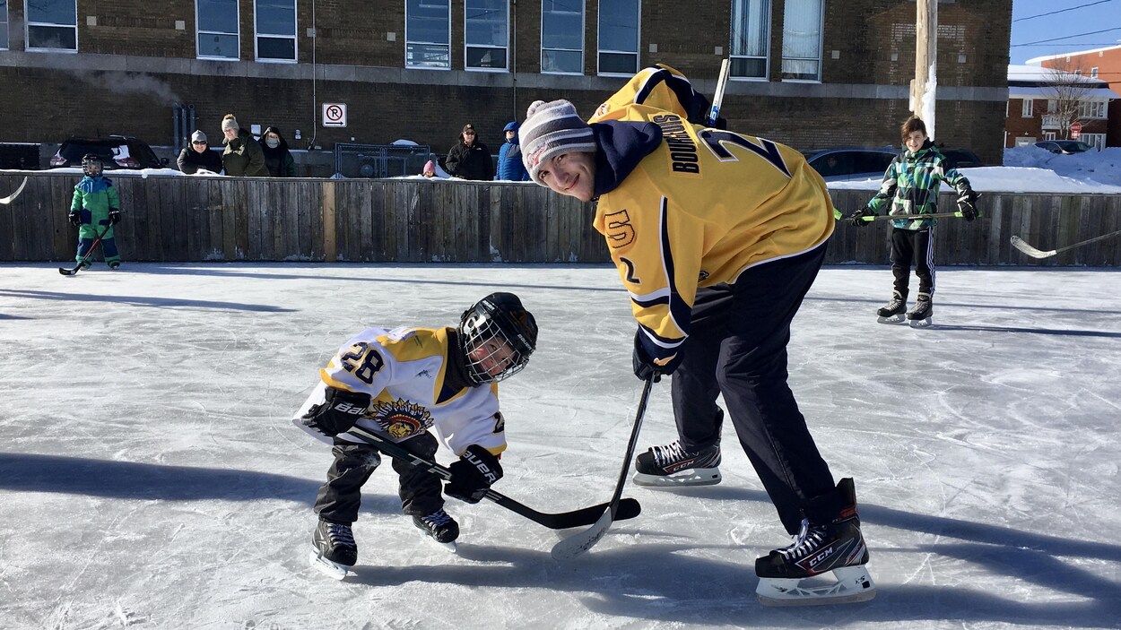 Un jeune enfant à la mise au jeu avec un joueur des Cataractes.