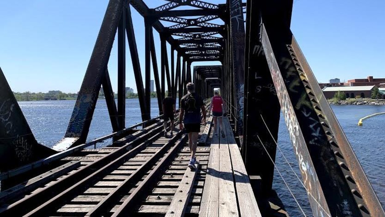 Trois personnes sur un pont ferroviaire.
