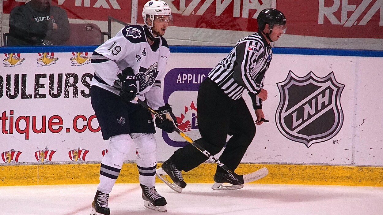 Le joueur #19 sur la glace avec un arbitre en train de patiner.