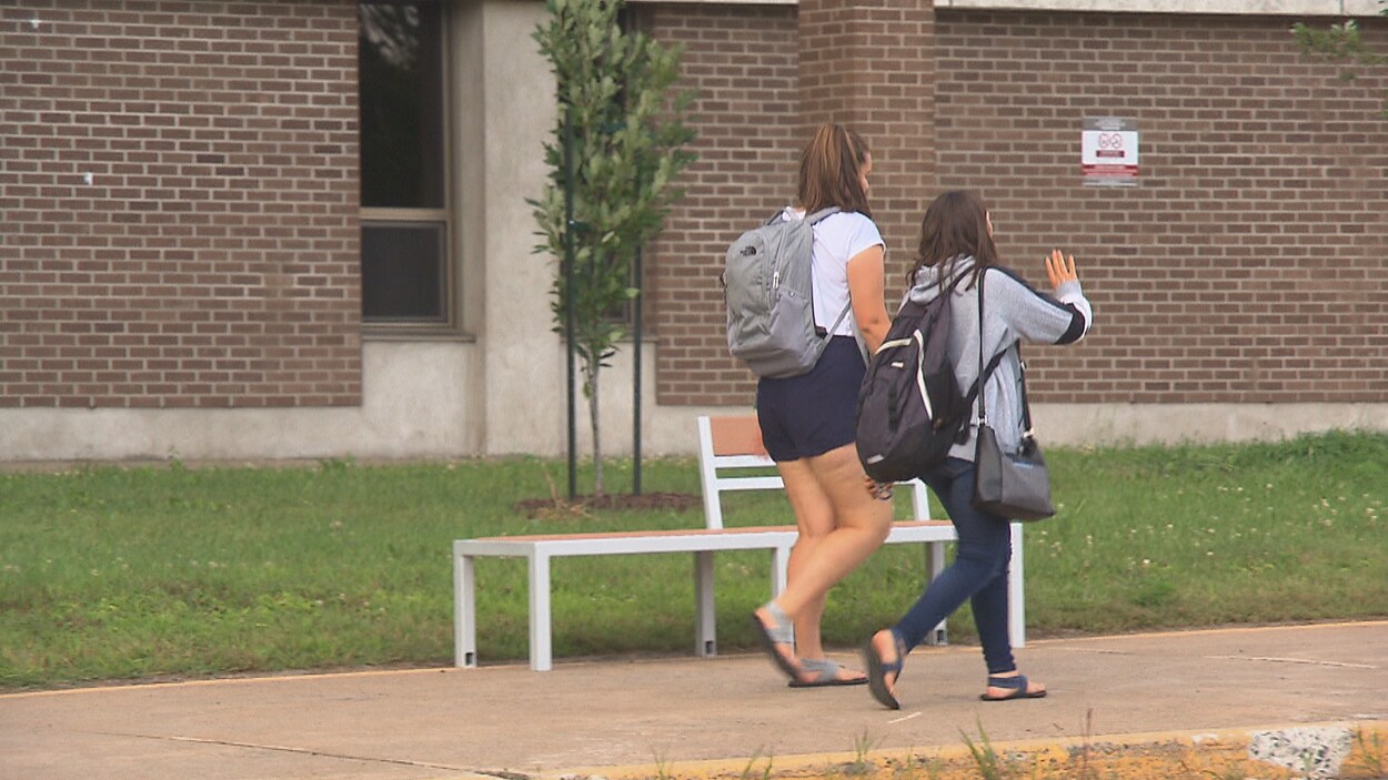 Deux étudiantes marchent sur le trottoir devant un cégep.